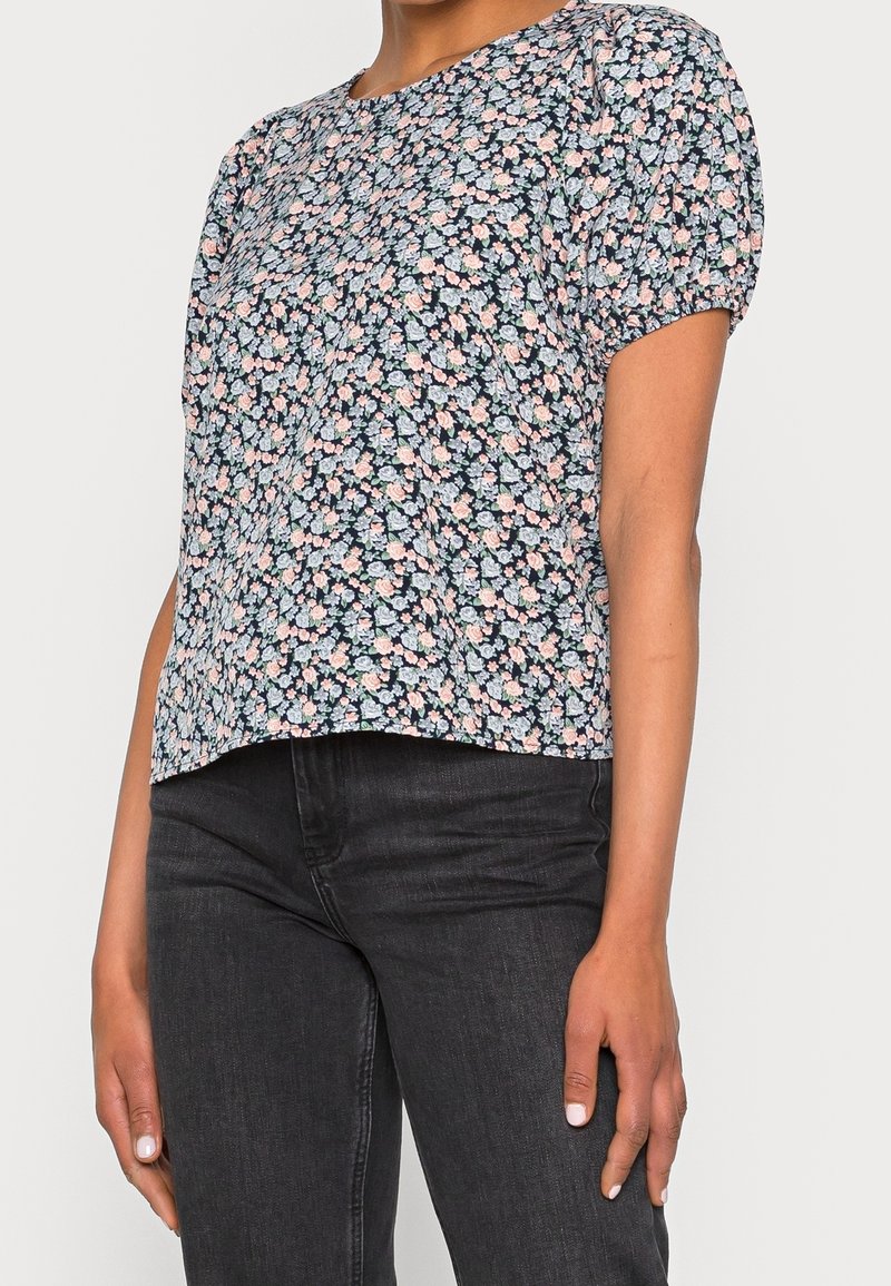 Top floreale a maniche corte in blu navy, con un denso motivo di fiori rosa e blu su uno sfondo scuro. Tessuto morbido, scollatura rotonda.