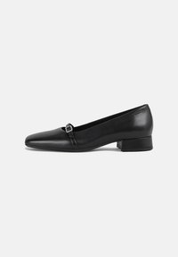 Chaussure plate en cuir noir avec un bout pointu et un petit talon carré. Présente une sangle décorative avec une boucle carrée pour le détail.