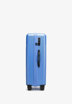 Duża niebieska twarda walizka z teksturowaną powierzchnią, podwójnymi suwakami, czarną rączką i czterema czarnymi kółkami dla łatwej mobilności.