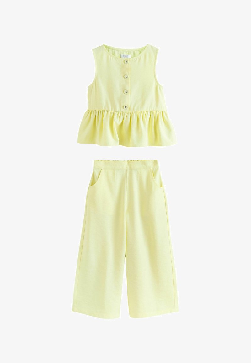 Haut sans manches jaune pâle à boutonnière avant avec taille à volants, associé à un pantalon large assorti avec poches latérales.