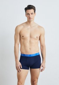 Dunkelblaue Boxerbriefs mit einem blauen Bund, der das "PUMA"-Logo trägt. Der Stoff ist glatt und hat ein eng anliegendes, körperbetontes Design.