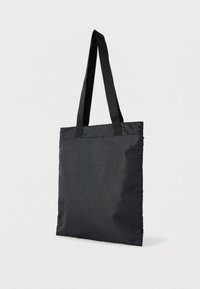 Black tote bag with subtle paisley pattern, featuring long black handles, standing against a white background.
