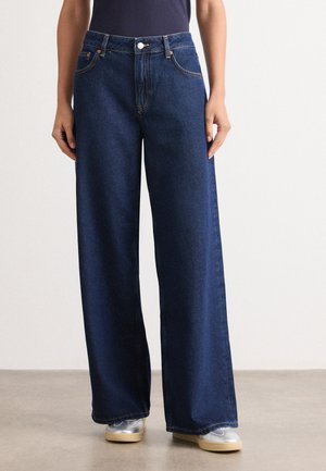 Wide-leg denim jeans in dark blue, with orange stitching, front pockets, and metal hardware for closure. Smooth texture and relaxed fit.