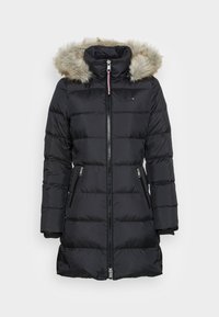 Černý prošívaný zimní kab át s kapucí lemovanou kožešinou, předním zipem, dvěma zipovými kapsami a manžetami s žebrováním, navržený pro chladné počasí.