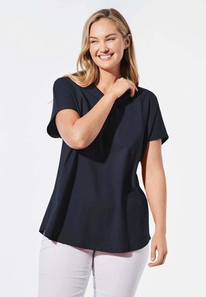Navy V-hals T-shirt van gladde stof met korte mouwen en een relaxte pasvorm, gecombineerd met lichtgekleurde broeken.