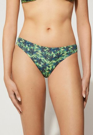 Grüner Bikini-Unterteil mit Palmenblattmuster. Der Stoff hat eine glatte Textur und einen منخفضen Schnitt, der für eine tropische Ästhetik gestaltet ist.