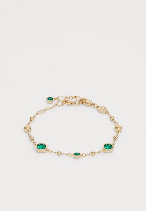 Gouden armband met groene edelstenen afgewisseld met ronde gouden kralen. Voorzien van een veilige sluiting met een klein logo tag.