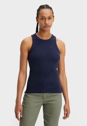 Mørkeblå ribbet tanktop med rund hals og ærmeløs design, parret med olivengrønne bukser. Glat tekstur og tætsiddende silhuet.