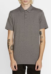 Polo shirt gris à manches courtes avec un col, patte de boutonnage à trois boutons et un motif texturé subtil. Style ajusté avec un accent de logo sobre.