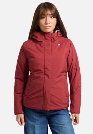 Giacca imbottita rossa con colletto alto e cappuccio, dotata di un piccolo logo sul petto e tasche laterali. Texture sintetica liscia.