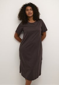 Robe à manches courtes, ample, en coton marron foncé. Col rond avec fentes sur les côtés au niveau de l'ourlet pour plus de liberté de mouvement. Texture lisse.