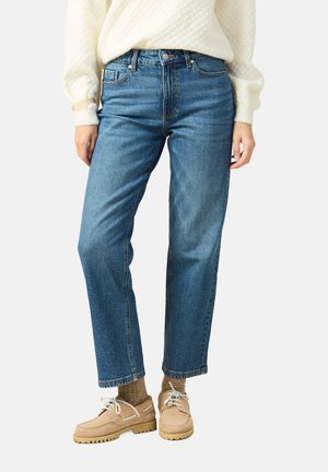 Lichtblauwe rechte jeans van denim, met vijf zakken, contrasterende stiksels en een hoge taille, gecombineerd met beige schoenen en sokken.