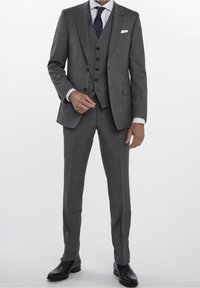 Costume gris trois pièces avec une veste à revers, un gilet ajusté et un pantalon droit ; complété par un pochette blanche et une cravate à motifs.
