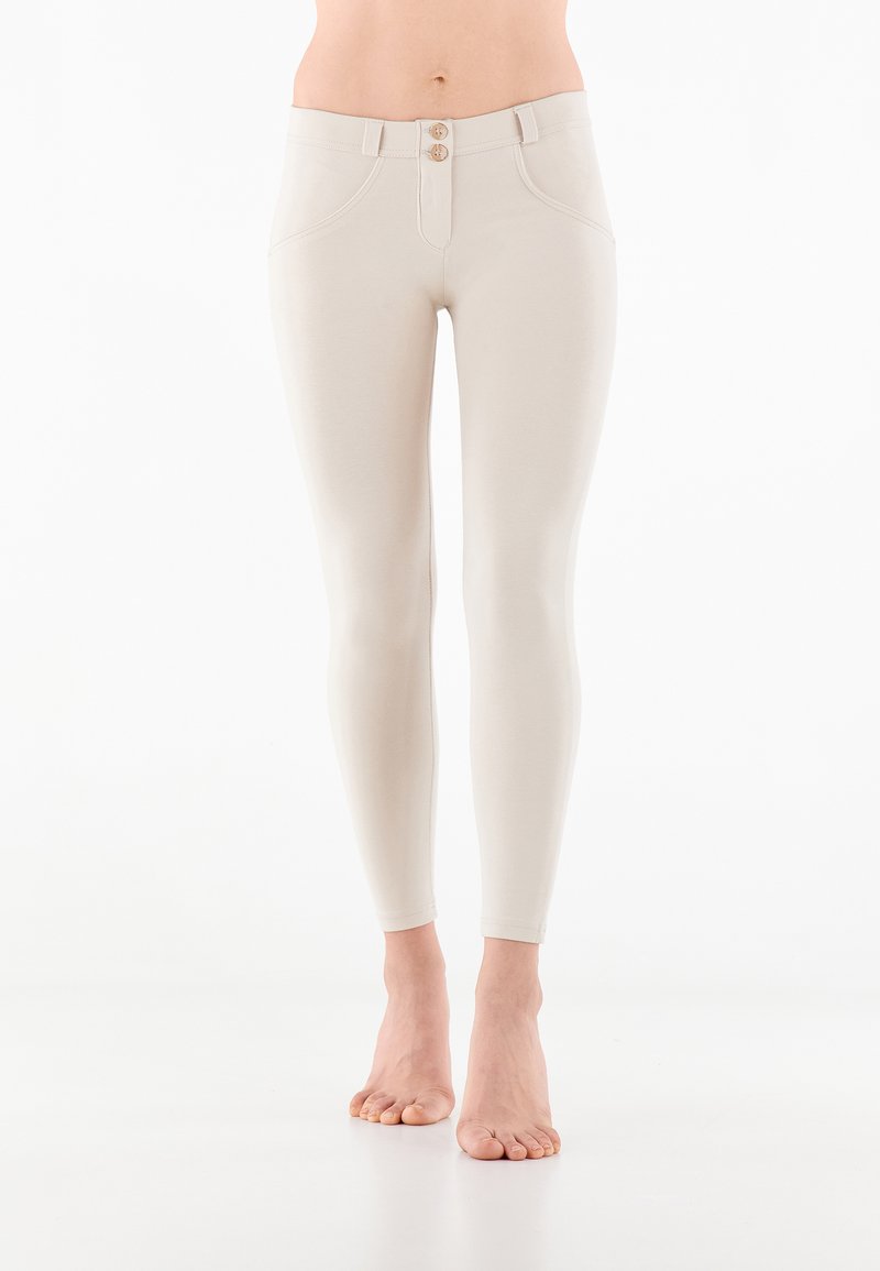 Leggins vaaleanruskeita, joissa on korkea vyötärö, kahden napin suljenta, hienovaraiset ompeleet ja kapea muotoilu, joka kapenee nilkoissa.