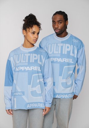 Zwei Models tragen blaue Sweatshirts mit der Aufschrift "MULTIPLY APPAREL" und der Zahl 15 in großen weißen Buchstaben.