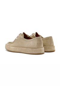 Zapatos de ante beige con punta redonda, diseño de cordones y acentos cosidos. Presenta un perfil bajo y un interior de cuero.
