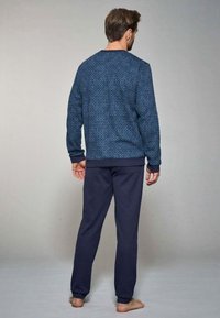 Set di abbigliamento da casa blu navy composto da una felpa decorata e pantaloni blu navy uni. La felpa ha un collo tondo e polsini a coste.