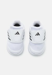 Bílé sportovní boty s prodyšným síťovaným svrškem, polstrovaným límcem a nastavitelným páskem. Černé detaily u paty a loga.