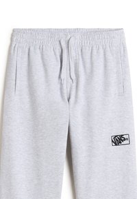 Grå sweatpants med elastisk midja, dragsko, sidofickor och en svart Vans-logotyp närmast fållen. Mjuk tygstruktur.
