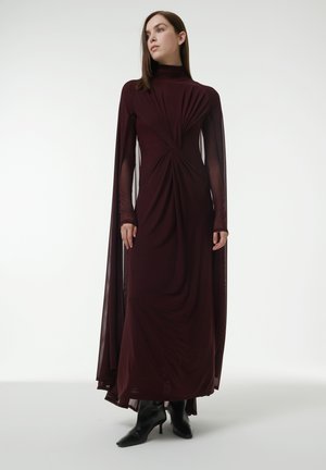 Burgunderfarbenes langes Kleid mit hohem Ausschnitt, drapiertem Oberteil und transparenten langen Ärmeln. Der Stoff weist aufwendige Faltungen und eine glatte Textur auf.