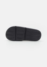 Sort gummisål med et tekstureret fiskebensmønster, der har tre distinkte sektioner og det præget mærkenavn "JACK & JONES."