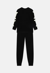 Schwarzes Schlafanzugset bestehend aus einem Langarmshirt und einer Hose. Weiße Knochen-Grafik auf den Ärmeln, aus weichem Stoff mit glatter Textur.