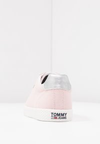 Rosa canvas sneakers med en metallic silver hälaccent och en texturerad vit sula. Har en logotypetikett på baksidan.