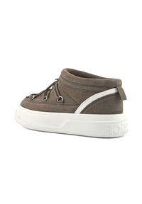 Zapatilla de ante marrón hasta el tobillo con suela de goma blanca gruesa y diseño de cordones, vista de lado sobre un fondo blanco.