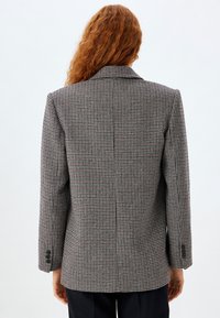 Karierte Blazer in Grau-, Schwarz- und Rottönen; strukturiertes Design mit Reverskragen und vier Knopfbündchen; strukturierter Stoff mit tailliertem Schnitt.