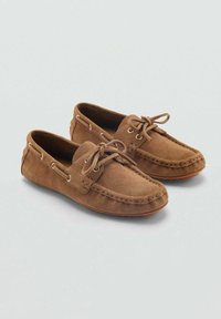 Mocassini in suede marrone con punta rotonda, lacci nella parte anteriore e cuciture decorative lungo i bordi. Suola in gomma per flessibilità.