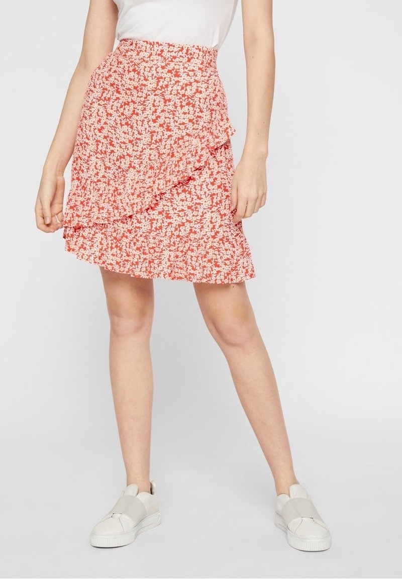 Röd blommig midikjol med lager-på-lager volangdesign, elastisk midja, lättviktsmaterial, kombinerad med vita slip-on skor.