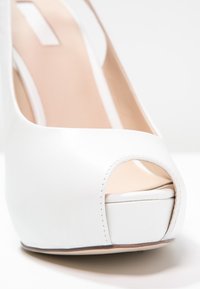Scarpa con tacco alto bianca, con design open toe, esterno in pelle liscia, punta piattaforma e fodera interna di un tenue beige a contrasto.