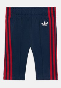 Shorts de sport bleu marine avec des rayures rouges sur les côtés, dotés d'une taille élastique et d'un logo brodé blanc sur le côté gauche.