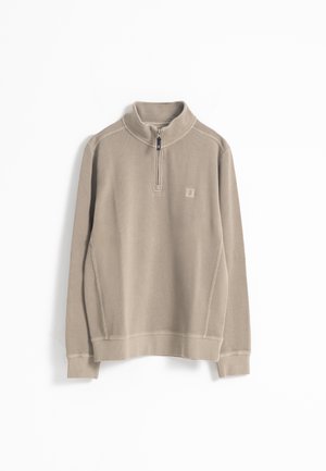 Sudadera de color beige, con cuello de canalé, cierre de media cremallera en la parte delantera, manga larga, textura suave, con un pequeño logo en el pecho.