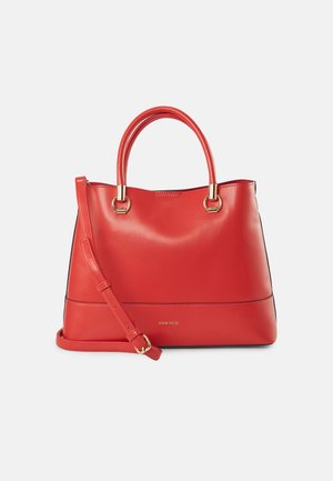 Sac à main en cuir rouge avec deux poignées rondes et une bandoulière détachable, ferrures dorées et finition lisse sur fond blanc.