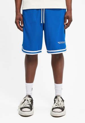 Blå basketballshorts laget av mesh-stoff, med hvite striper ved kanten og merkevaretekst. Sammen med svarte joggesko og hvite sokker.