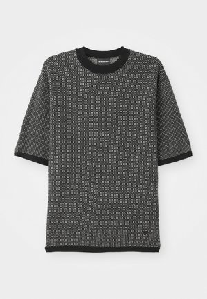Camiseta de punto de manga corta en blanco y negro con un patrón texturizado, cuello redondo de canalé negro y puños y dobladillo negros sólidos.