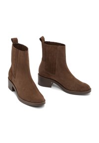 Bruna mockaskinnsankelboots med rund tå och en måttlig klack. Har elastiska sidopaneler och en dragflik för enkel påtagning.