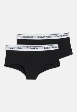 Dve čierne chlapčenské boxerky Calvin Klein s bielymi elastickými pásmi v páse s logom Calvin Klein.