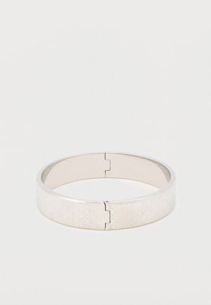 Sølv armbånd med et geometrisk ætset mønster. Glat, poleret overflade; hængslet åbning; slankt, cirkulært design.