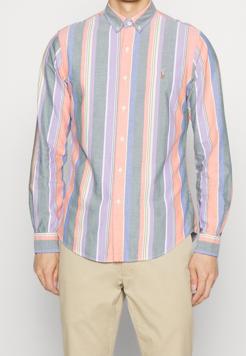 Knapplång skjorta med vertikala ränder i rosa, grått, lavendel och ljusblått. Har en spetsig krage och en liten logotyp på bröstet.