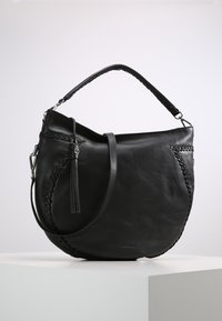 Czarna skórzana torebka z plecionymi akcentami, okrągłym kształtem, regulowanym paskiem na ramię i detalem w postaci frędzla. Gładka struktura i minimalistyczny design.