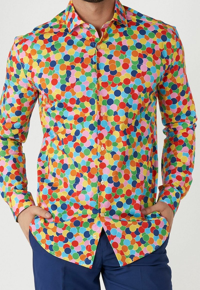 Camisa de botones colorida con un patrón de lunares en rojo, amarillo, azul, verde y rosa sobre un fondo blanco. Tejido de algodón.