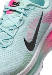 Light blue running shoe with a textured upper, black Nike logo, pink accents, and white sole, featuring a sleek design and cushioned support.