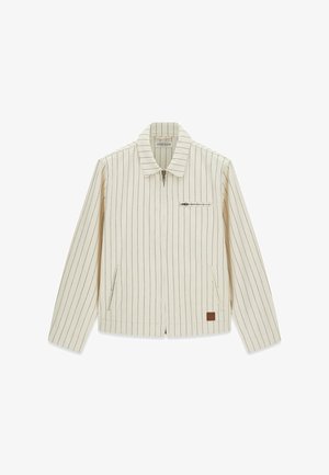 Veste zippée crème pour hommes avec fines rayures verticales noires, col, poche poitrine zippée, poches latérales et un petit patch marron près de l'ourlet.