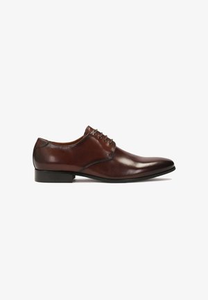 Zapato de vestir de cuero marrón con textura suave, punta afilada y seis ojales. Cuenta con un tacón bajo negro y un sutil detalle de costura.