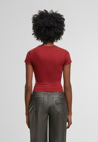 Rode slim-fitting T-shirt met korte mouwen, gecombineerd met grijze wijde jeans met geborduurde details op de rechter achterzak.
