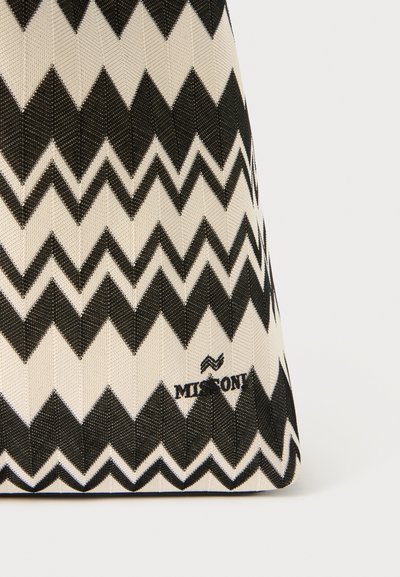 Textile bag featuring a black and white zigzag pattern, a flat base, and a logo at the bottom corner. Made from durable materials.