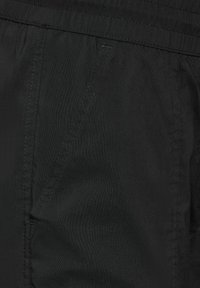 Schwarze Stoffshorts mit elastischem Taillenbund, Seitentaschen mit schrägen Nähten und einer glatten, matten Textur.