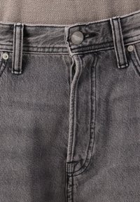 Šedé džíny z denimu s texturovaným povrchem, s knoflíkovým zapínáním, kovovým hardwarovým komponentem a kontrastním prošíváním podél švů.